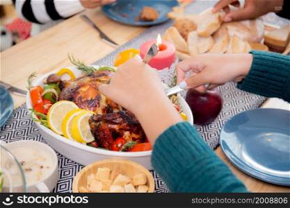 Closeup hands of children using knife slicing meat of turkey roasted on dishes for eating at home on thanksgiving eve day, celebration of xmas with dining with family, new year, festive and holiday.