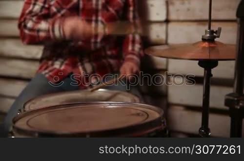 Closeup hands of drummer with sticks playing on the metal hi-hat cymbals at concert. Young musician with drumsticks playing drums and cymbals.