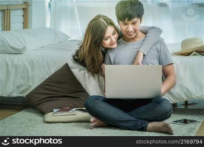 Closeup Happy Asian Lover or couple talking and smiling when using technology laptop on the bed in bed room at modern home, young women pointing to the nose of boyfriend, Lover and life style concept,