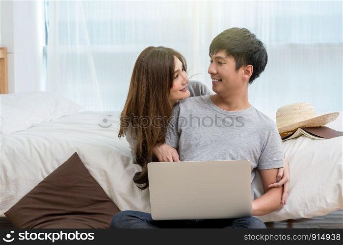 Closeup Happy Asian Lover or couple talking and smiling when using technology laptop on the bed in bed room at modern home, young women pointing to the nose of boyfriend, Lover and life style concept,
