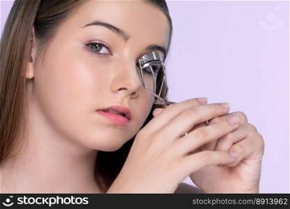 Closeup happy young charming brunette holding eyelash curler in her hand as makeup accessory. Beautiful  girl applying eyelash curler in studio with isolated background for copyspace.. Closeup happy young charming brunette holding eyelash curler in her hand.