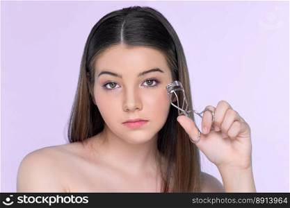 Closeup happy young charming brunette holding eyelash curler in her hand as makeup accessory. Beautiful  girl applying eyelash curler in studio with isolated background for copyspace.. Closeup happy young charming brunette holding eyelash curler in her hand.