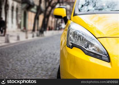 Closeup headlight of modern sport yellow car. Car exterior details over city background. Concept of expensive, sports auto