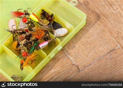 closeup heaps of fishing bait lures in box on wooden background