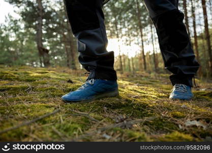 Closeup hiker foot in trekking boots walking among forest trail. Active lifestyle and mindfulness during woodland journey. Closeup hiker foot in trekking boots walking in forest