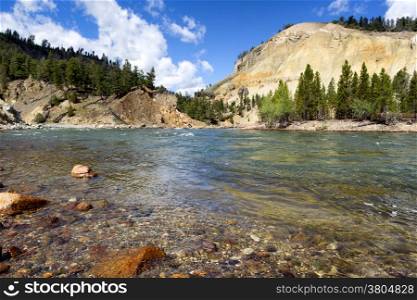 Closeup horizontal image of Yellowstone River running through the canyon during summer day with blue sky and clouds