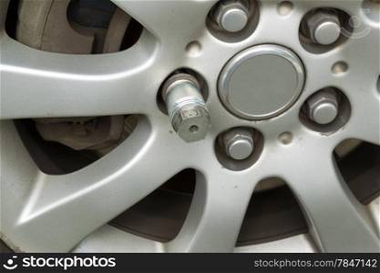 Closeup horizontal photo of locking wheel nut key on car wheel rim