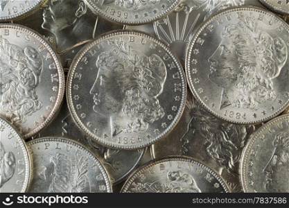 Closeup horizontal photo of several United States Silver Dollars, obverse side up, piled up
