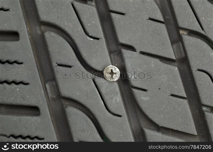 Closeup horizontal photo of wood screw embedded into car tire tread &#xA;&#xA;