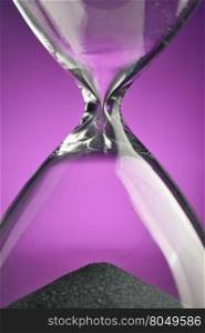 Closeup hourglass on purpple background