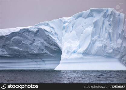 Closeup iceberg with ice cave made of blue shimmering ice wall, floating in Antarctic sea