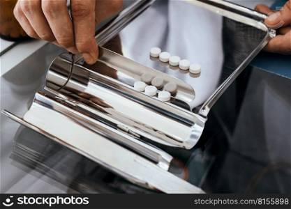 Closeup image hand of pharmacist counting and arrange pills on qualified stainless counting tray with spatula in pharmacy. Pharmacist prepare medication in stainless tray by prescription at drugstore.. Pharmacist prepare pills in qualified counting tray by prescription at drugstore