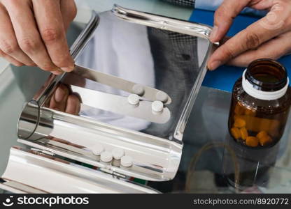 Closeup image hand of pharmacist counting and arrange pills on qualified stainless counting tray with spatula in pharmacy. Pharmacist prepare medication in stainless tray by prescription at drugstore.