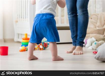 Closeup image of 10 months old baby boy making first steps at home