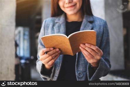 Closeup image of a beautiful asian businesswoman holding and looking at a notebook