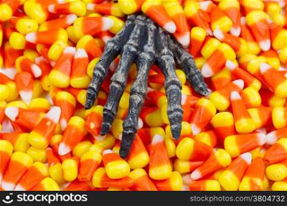 Closeup image of a scary hand coming out of pile of candy corn