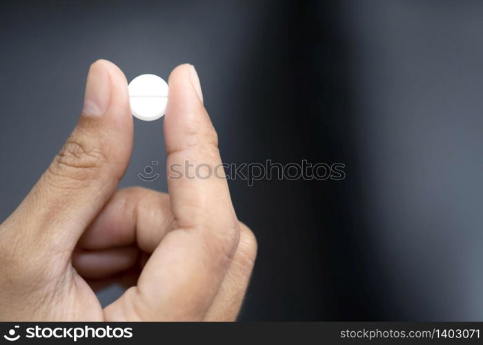 Closeup image of a woman holding a white pill and a glass of water