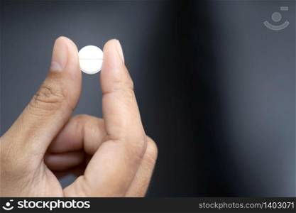 Closeup image of a woman holding a white pill and a glass of water