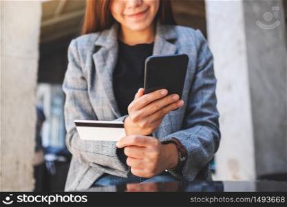 Closeup image of a woman using credit card for purchasing and shopping online on mobile phone
