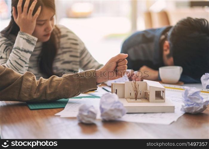 Closeup image of an angry and stressed architects try to destroy an architecture model on the table by hand when fail at work