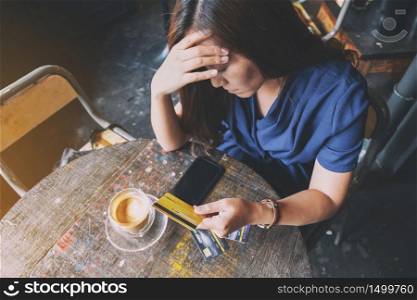 Closeup image of an Asian woman get stressed and broke while holding credit card