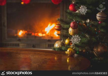 Closeup image of baubles on Christmas tree in front of burning fireplace. Beautiful Christmas background