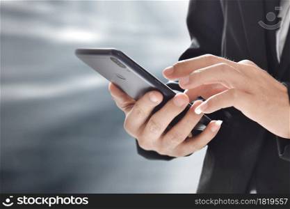 Closeup image of businessman holding and using mobile phone over blur background.