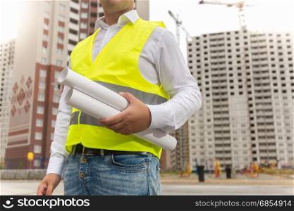 Closeup image of construction engineer holding blueprints