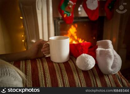 Closeup image of cup of tea on sofa at fireplace