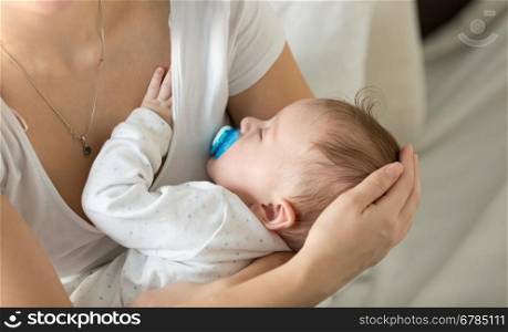 Closeup image of cute 3 months old baby sleeping on mothers hands