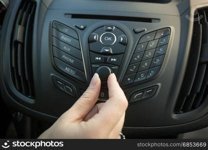 Closeup image of female driver adjusting car stereo system