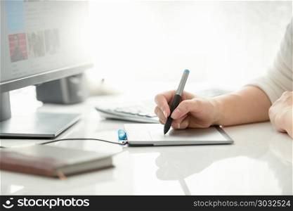 Closeup image of female graphic designer holding stylus and drawing on graphic tablet. Closeup photo of female graphic designer holding stylus and drawing on graphic tablet