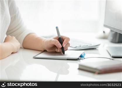 Closeup image of female hand drawing with stylus on graphic tablet. Closeup photo of female hand drawing with stylus on graphic tablet