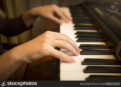 Closeup image of female hands playing on piano