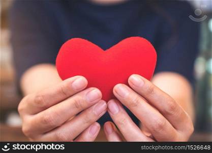 Closeup image of hands holding a red heart sign