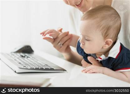Closeup image of little baby boy looking at keyboard in office. Closeup photo of little baby boy looking at keyboard in office