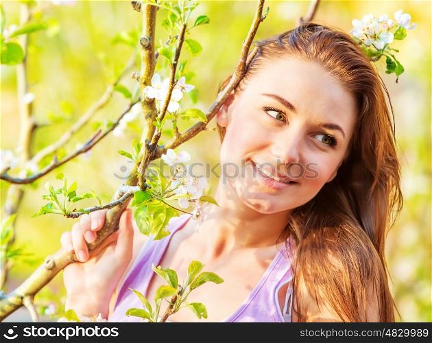 Closeup image of lovely girl spending time in spring park, cherry tree blossom, enjoying nature, peace and harmony concept
