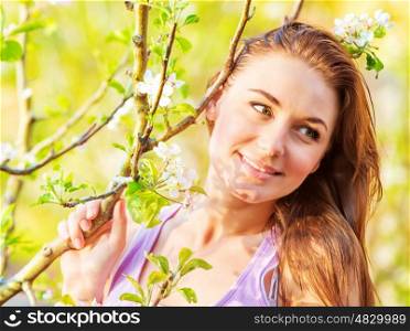 Closeup image of lovely girl spending time in spring park, cherry tree blossom, enjoying nature, peace and harmony concept