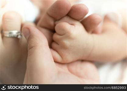 Closeup image of man holding newborn baby\s hand