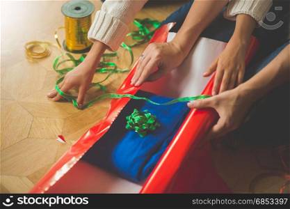 Closeup image of mother and daughter making Christmas present and wrapping sweater in wrapping paper