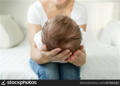 Closeup image of mother's hands holding head of sleeping 3 months old baby boy