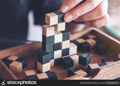 Closeup image of people playing and building wooden puzzle game