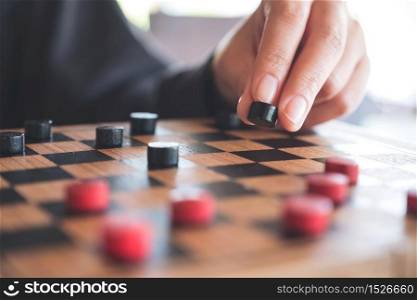 Closeup image of people playing and moving checkers in a chessboard