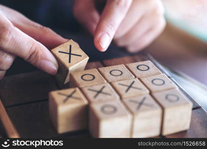 Closeup image of people playing wooden Tic Tac Toe game or OX game