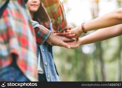 Closeup image of people putting their hands together in the outdoors