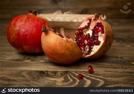 Closeup image of pomegranates and basket lying on old wooden desk