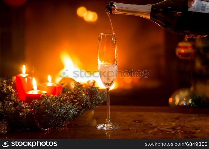 Closeup image of pouring fizzy champagne in crystal glass on table