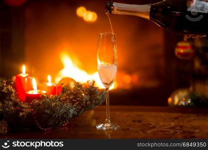 Closeup image of pouring fizzy champagne in crystal glass on table