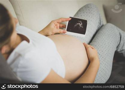 Closeup image of pregnant woman looking at ultrasound embryo image