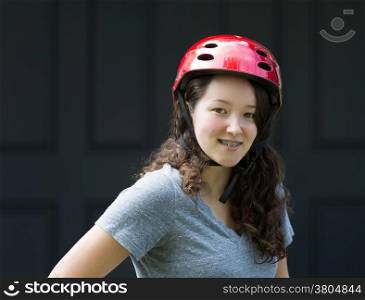 Closeup image of teenage girl, looking forward with helmet on, with home front door in background